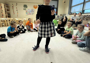 dziewczynka stoi w środku kołą i trzyma plastikowy winogron