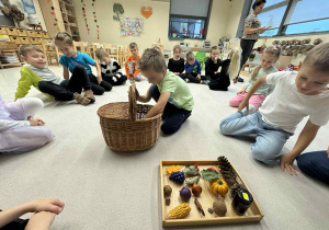 chłopiec jest w środku koła i wyciąga z koszyka dary jesieni