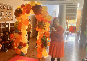 pani ubrana na pomarańczowo trzyma mikrofon i rozpoczyna dyniowy pokaz mody