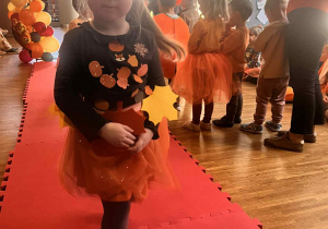 dziewczynka w dyniowej opasce i stroju przechodzi przez wybieg