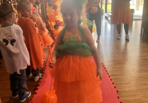 dziewczynka prezentuje samodzielnie wykonany przez tatę strój dyniowy, przechodząc po wybiegu