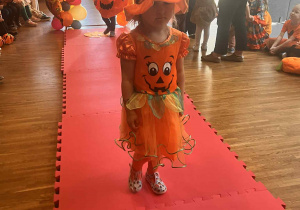 dziewczynka w stroju dyni przechodzi przez wybieg