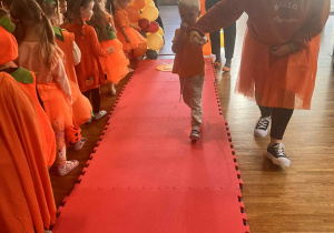 chłopiec idzie po wybiegu prowadzony za rękę przez panią