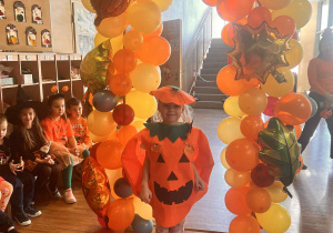 dziewczynka w stroju dyni pozuje na sciance z balonami