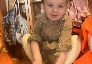 uśmiechnieta dziewczynka siedzi w dyniowym cylindrze