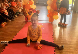 dziewczynka prezentuje w dyniowym stroju szpagat