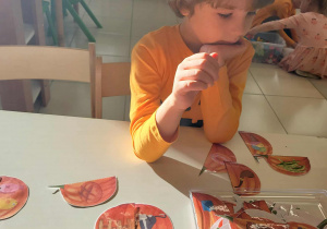 chłopiec układa z dyniowej połówek wyrazowe rymy