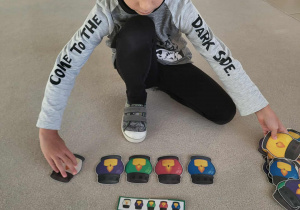 chłopiec układa sylwety zniczy według wzoru