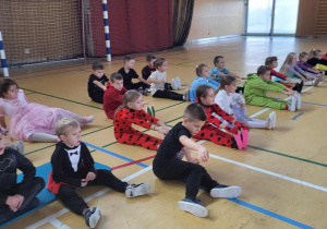 dzieci wykonują ćwiczenia na siedząco