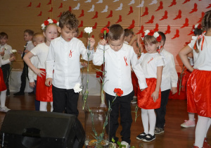 Dzieci wkładają kwiaty do wazonu