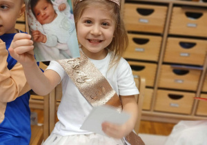 Dziewczynka prezentuje zdjęcie z dzieciństwa