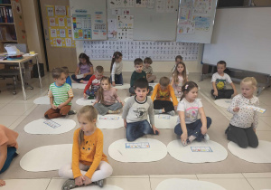 dzieci siedzą na dywanikach