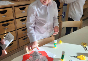 chłopiec przykleja orła na czerwonym tle