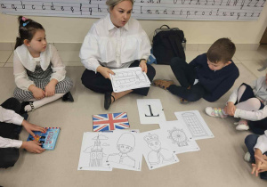 Pani nauczycielka angielskiego pokazuje dziecom kolorowanki z symbolami Wielkiej Brytanii