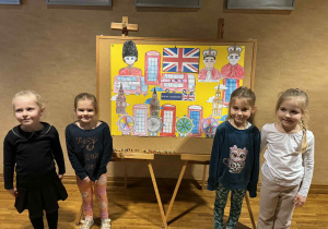 dziewczynki pozuja po lewej i prawej stronie do zdjęcia na tle plakatu z symbolami Wielkiej Brytanii