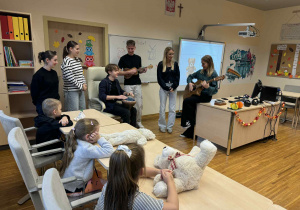 dzieci trzymają misie i uczą się piosenki w języku niemieckim,śpiewaną i grana przez uczniów