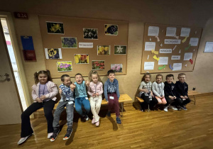 dzieci siedzą na ławce przed klasą