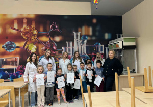 dzieci trzymają kolorowanki wraz z Panią od angielskiego, Pani od Chemi i jej uczenicami pozują do zdjęcia