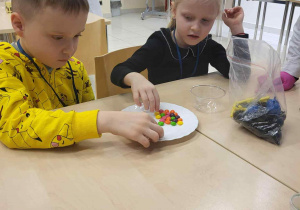 chłopiec i dziewczynka siedzą przy stole i wykonują eksperyment