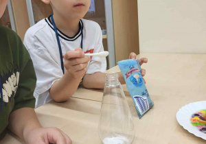 chłopiec nasypuje do pojemnika sodę oczyszczoną