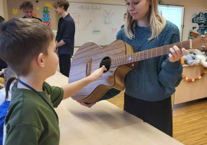 chłopiec gra na gitarze, którą trzyma uczenica