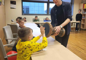 chłopiec uderza w bębenek, który trzyma uczeń