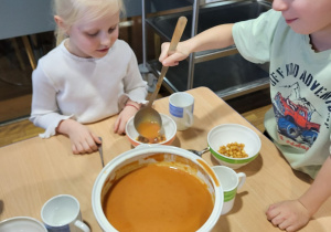 Chłopiec nalewa dziewczynce zupe