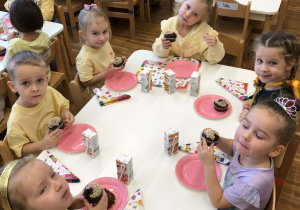 dzieci siedza przy stole i jedza babeczki