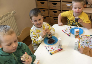 dzieci siedza przy stole i jedza babeczki