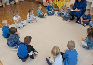 dzieci siedza w kole i słuchaja pani