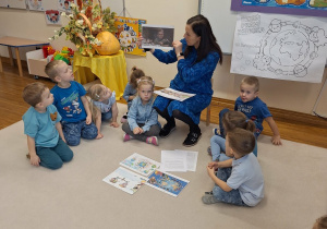 dzieci siedza w kole i słuchaja pani