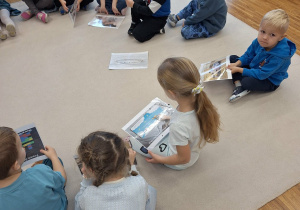 dzieci trzymaja w dłoniach karty z prawami dziecka