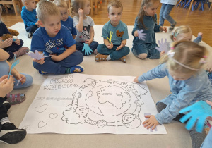 dzieci przyklejają odrysowane dłonie na kartkę