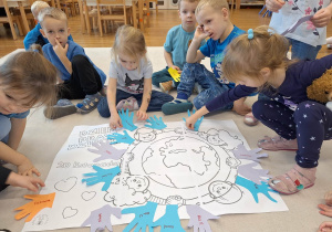 dzieci przyklejają odrysowane dłonie na kartkę