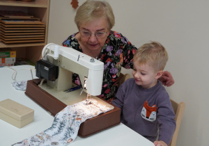 chłopiec siedzi przy maszynie do szycia