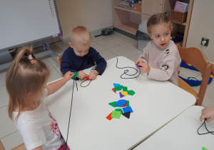 dzieci nawlekają kolorowe guziki