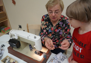 pani pokazuje chłopcu części maszyny do szycia