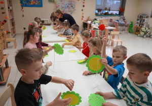 dzieci przewlekają sznurki przez kwiaty