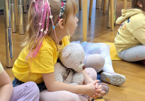 dziewczynka siedzi z Misiem Krzysiem