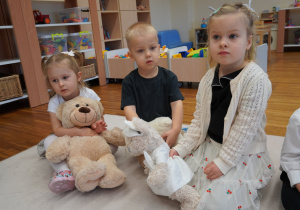 dzieci siedzą z misiami na dywanie