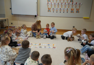 dzieci siedzą z misiami na dywanie