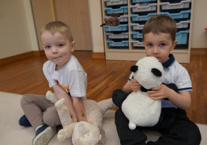 chłopcy siedzą z misiami na dywanie