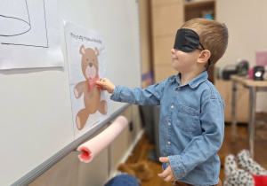 chłopiec dopasowuje kokardę do misia