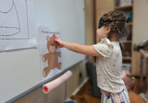 dziewczynka dopasowuje kokardę do misia