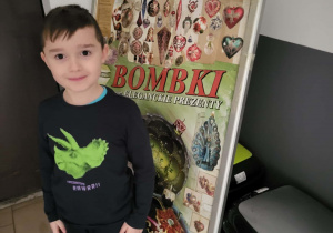 chłopiec stoi przy plakacie z bombkami