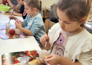 dziewczynka maluje klejem bombkę