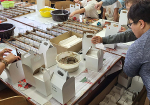 dzieci z paniami pakują ozdobione bombki w pudełka