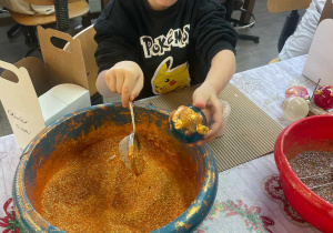 chłopiec posypuje brokatem bombkę