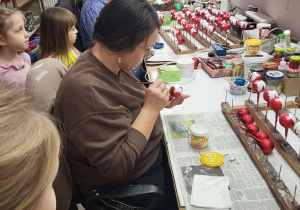pani własnoręcznie dekoruje szklaną bombkę