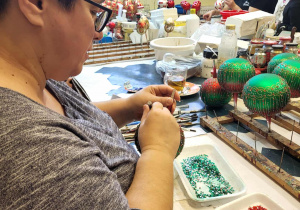 pani własnoręcznie dekoruje szklaną bombkę